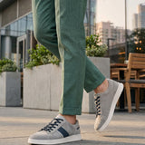 Lifestyle image of bugatti Fiero grey leather sneakers, with dark laces and a navy stripe detail.
