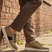 bugatti Fiero beige leather sneakers with black laces and a white sole, worn with brown trousers.
