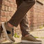 bugatti Fiero beige leather sneakers with black laces and a white sole, worn with brown trousers.
