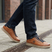 Lifestyle close-up of bugatti Fiero cognac leather sneakers with dark denim jeans on a city street.