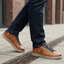 Lifestyle close-up of bugatti Fiero cognac leather sneakers with dark denim jeans on a city street.