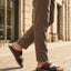 bugatti Cobie dark blue leather sandals with two straps, worn with brown trousers.