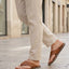 Lifestyle image of bugatti Cobie cognac leather thong sandals worn with casual tan pants in a city setting.