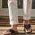 Lifestyle shot of bugatti Cobie comfort thong sandals in dark blue, worn with white casual pants.
