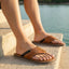 Lifestyle image of bugatti Cobie cognac leather thong sandals, with dark accent stripe and white soles.