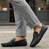 Lifestyle shot of bugatti Olexa dark blue leather slip-ons with a metal accent, worn with gray pants.