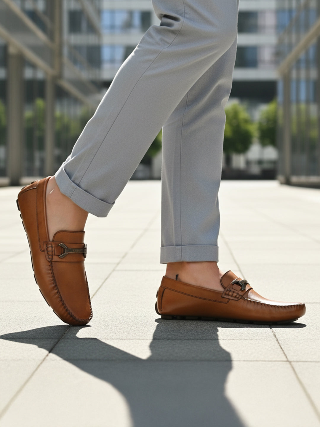 Lifestyle image of bugatti Olexa cognac leather slip-on shoes with rolled grey trousers.
