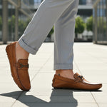 Lifestyle image of bugatti Olexa cognac leather slip-on shoes with rolled grey trousers.
