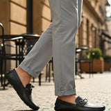 bugatti Olexa dark green leather slip-on shoe with decorative strap detail, worn with gray pants.
