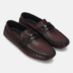 Burgundy leather slip-on shoes by bugatti, featuring a moc toe design and a decorative strap detail.