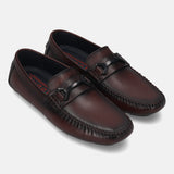 Burgundy leather slip-on shoes by bugatti, featuring a moc toe design and a decorative strap detail.
