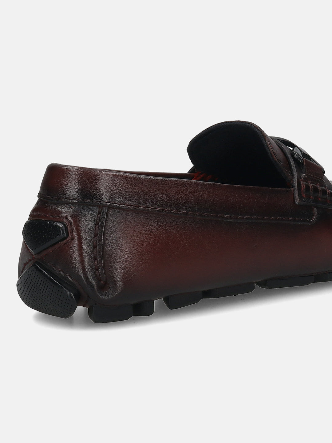 Burgundy leather loafer by bugatti with black rubber soles, seen from the back.