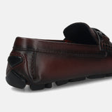 Burgundy leather loafer by bugatti with black rubber soles, seen from the back.