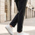 Lifestyle shot of bugatti Fogg white premium leather sneakers, paired with grey trousers and white pavement.
