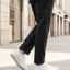 Lifestyle shot of bugatti Fogg white premium leather sneakers, paired with grey trousers and white pavement.
