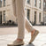 Lifestyle shot of bugatti Manfield sand-colored slip-on shoes in premium leather, worn with tan trousers on a city street.