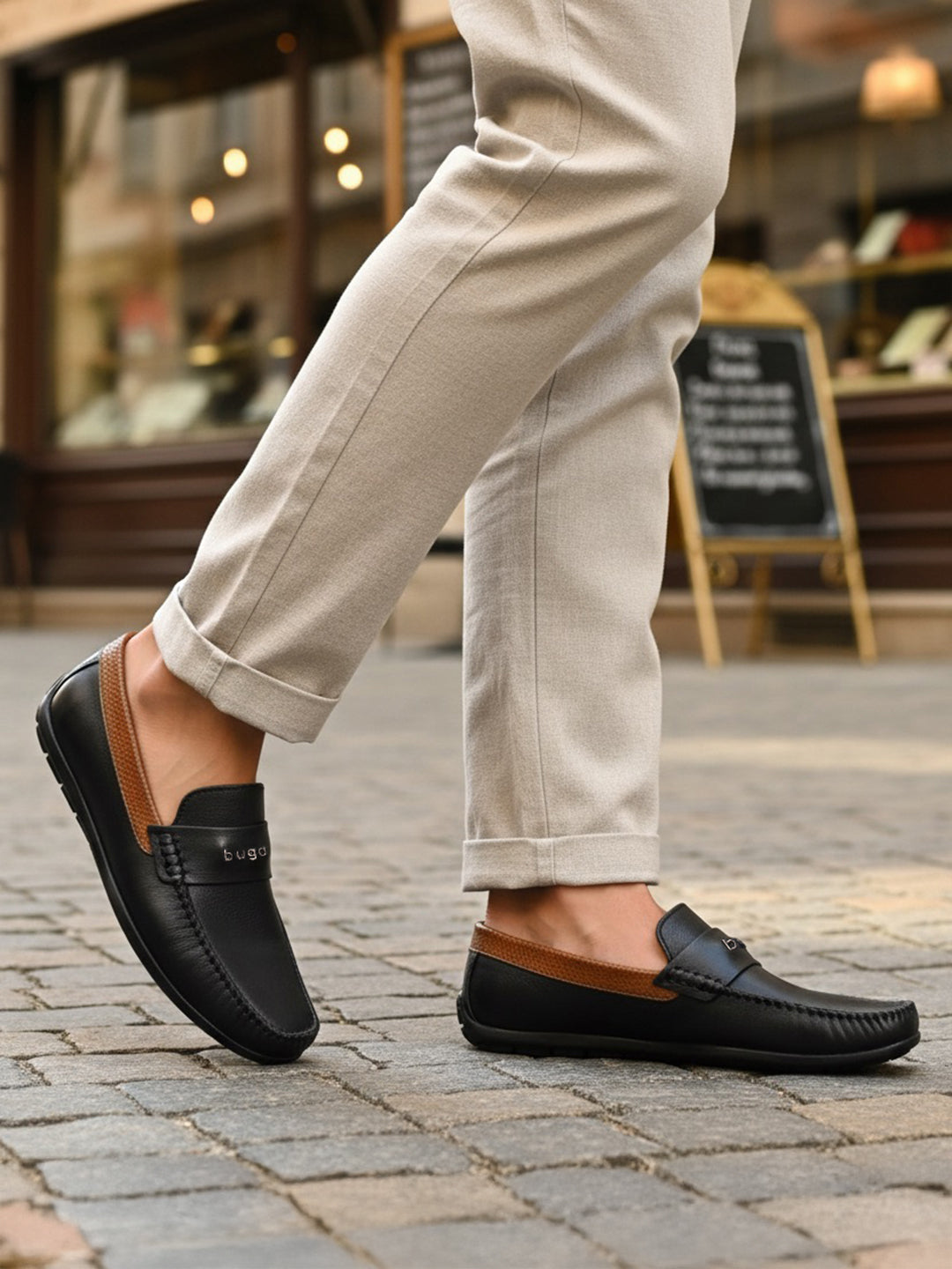 Lifestyle shot of bugatti Linex dark blue leather slip-on shoes with brown accents, paired with beige pants.

