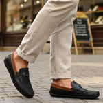 Lifestyle shot of bugatti Linex dark blue leather slip-on shoes with brown accents, paired with beige pants.

