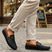 Lifestyle shot of bugatti Linex dark blue leather slip-on shoes with brown accents, paired with beige pants.
