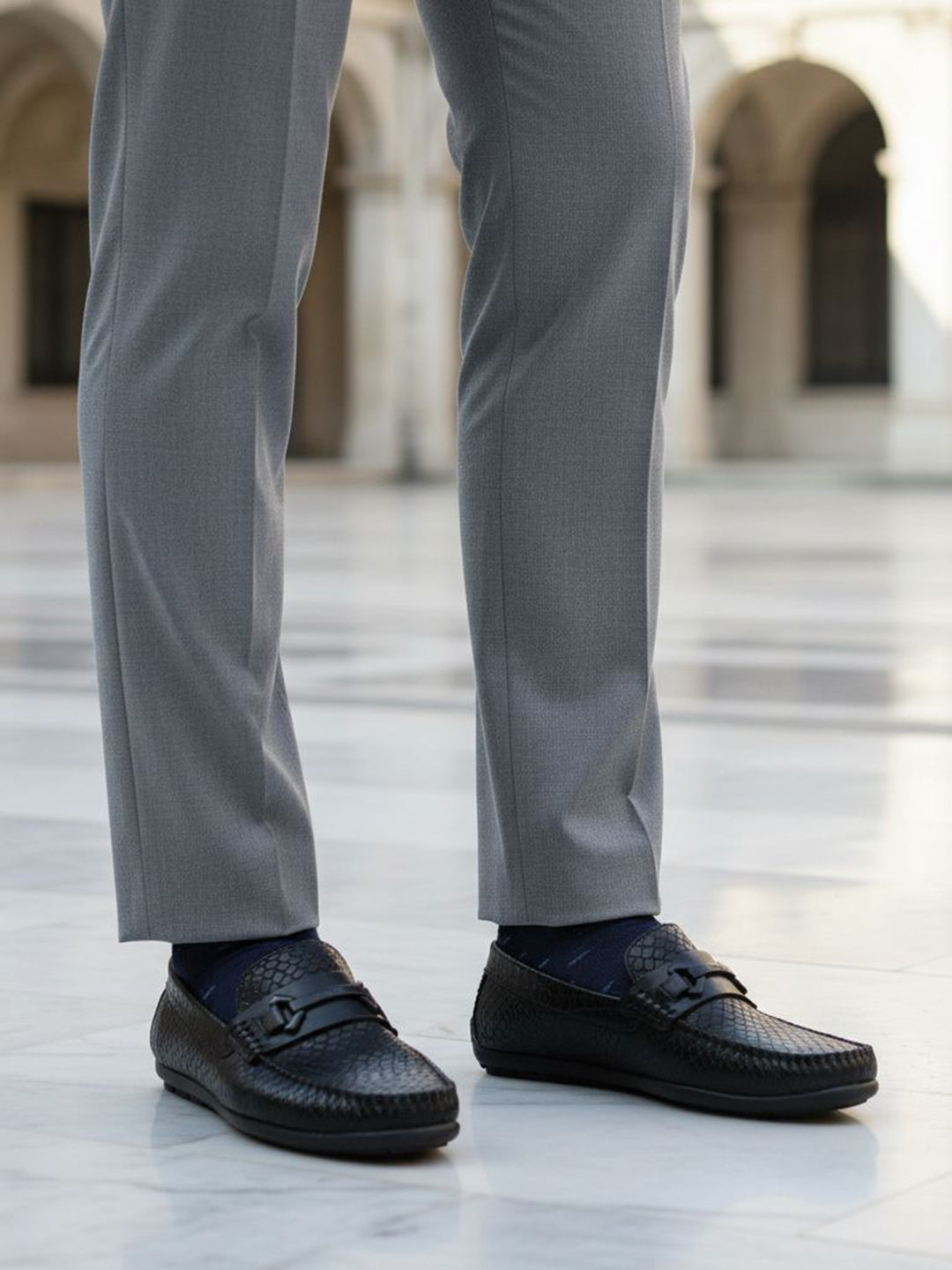 bugatti Linex black casual slip-ons in premium leather, worn with gray dress pants and dark socks.
