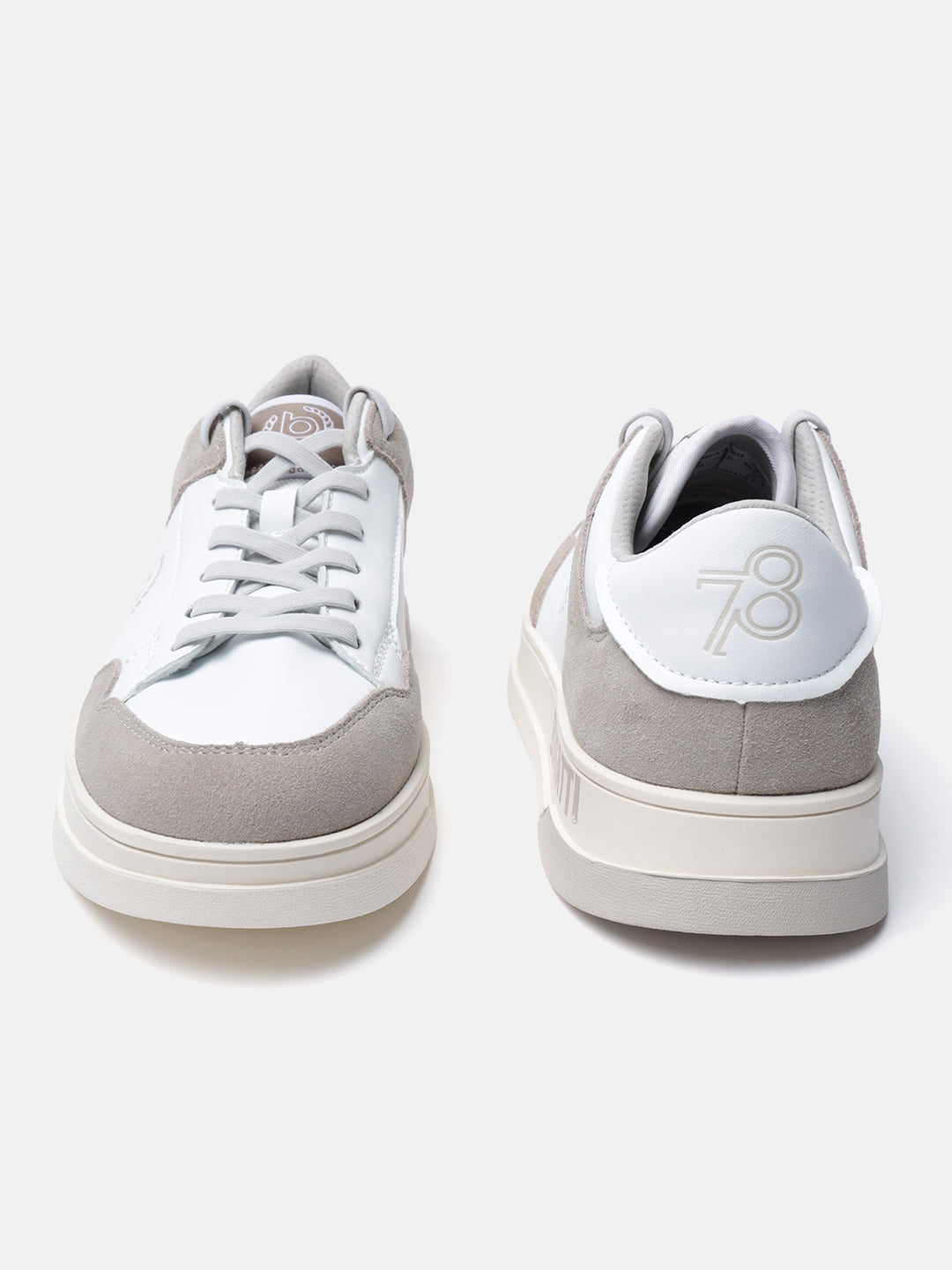 White leather sneakers by bugatti with gray suede accents and a contrasting platform sole.