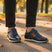 bugatti Ivar dark blue leather sneakers with brown stripe, white midsole, worn with black jeans.
