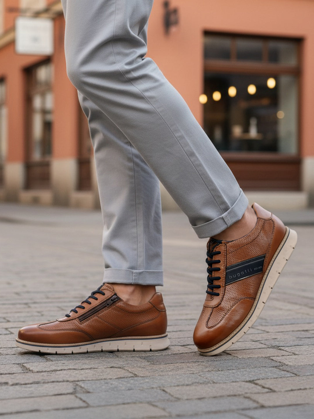 Lifestyle close-up of bugatti Sprinter cognac leather sneakers with black laces and zipper detail.
