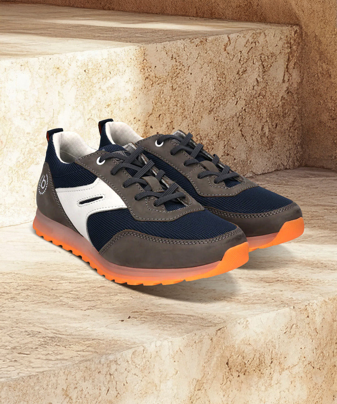 bugatti Cirino dark gray sneakers on stone steps, with white accents and orange translucent soles.