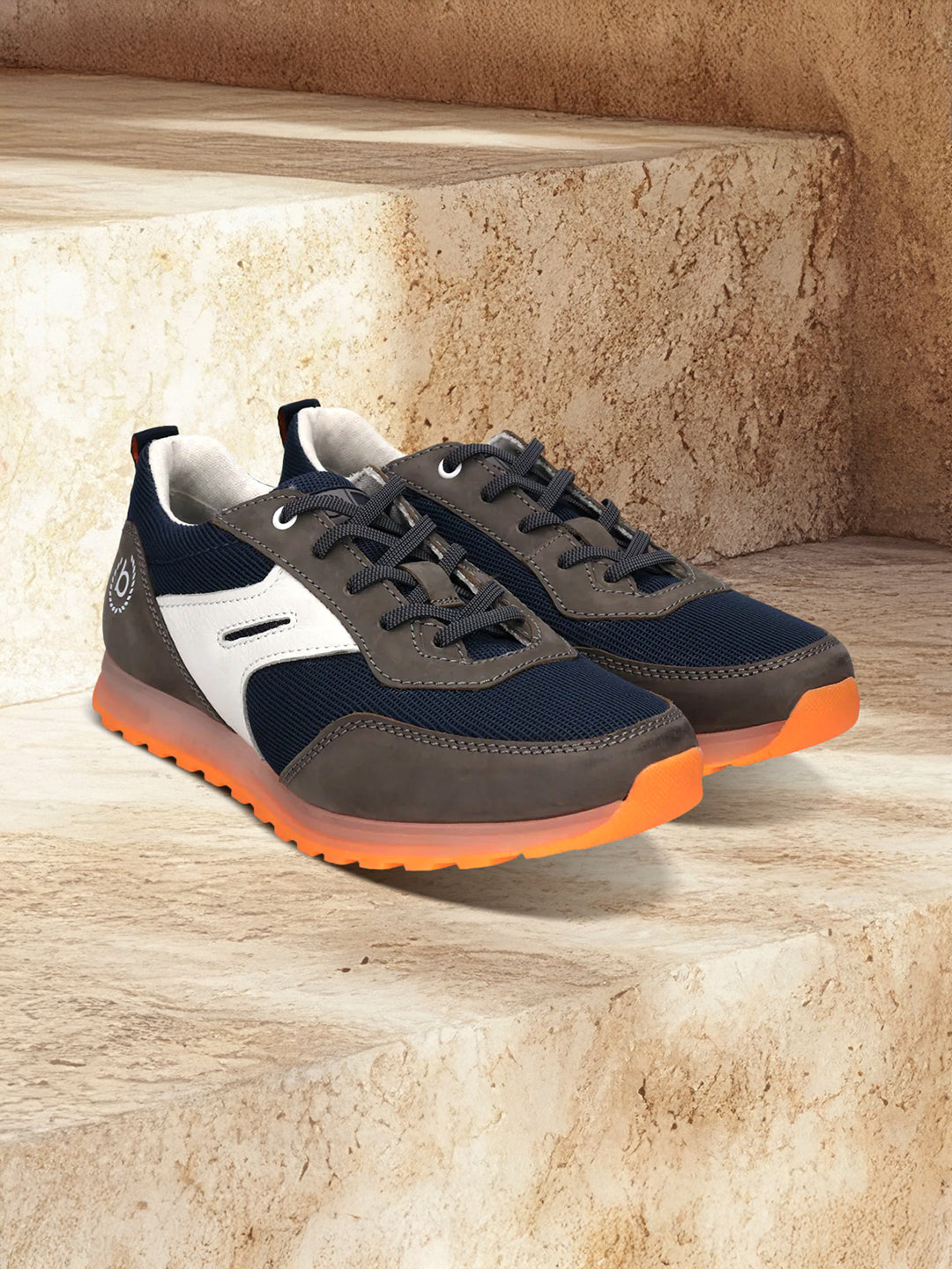 bugatti Cirino dark gray sneakers on stone steps, with white accents and orange translucent soles.