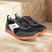 bugatti Cirino dark gray sneakers on stone steps, with white accents and orange translucent soles.
