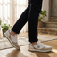 Lifestyle shot of bugatti Garnet Evo Sand Premium Leather Comfort Sneakers, paired with dark trousers, and set on a wood floor.