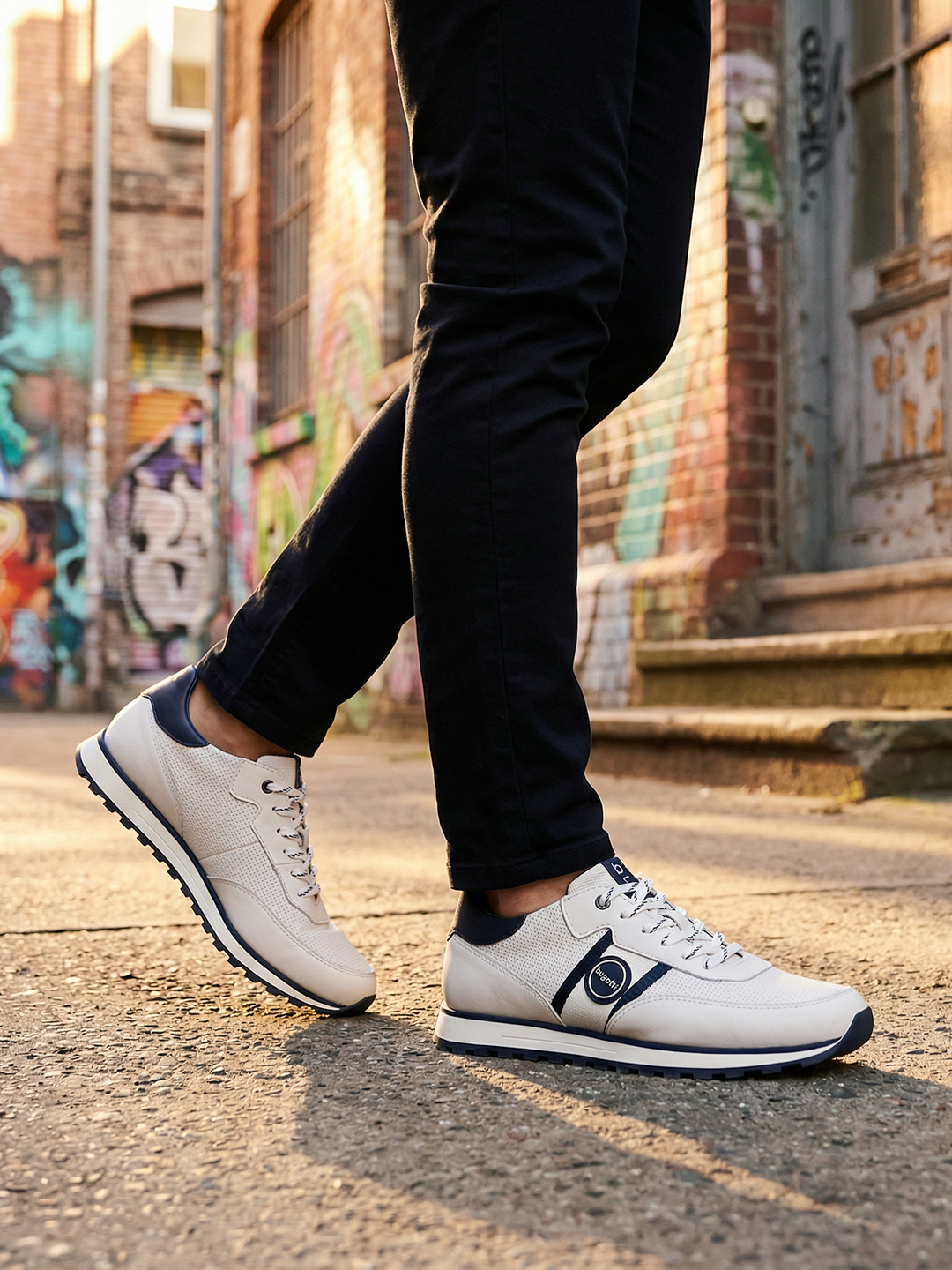 Lifestyle view of bugatti Garnet Evo white sneakers in premium leather, featuring navy accents and black pants.
