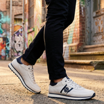 Lifestyle view of bugatti Garnet Evo white sneakers in premium leather, featuring navy accents and black pants.
