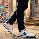 Lifestyle view of bugatti Garnet Evo white sneakers in premium leather, featuring navy accents and black pants.
