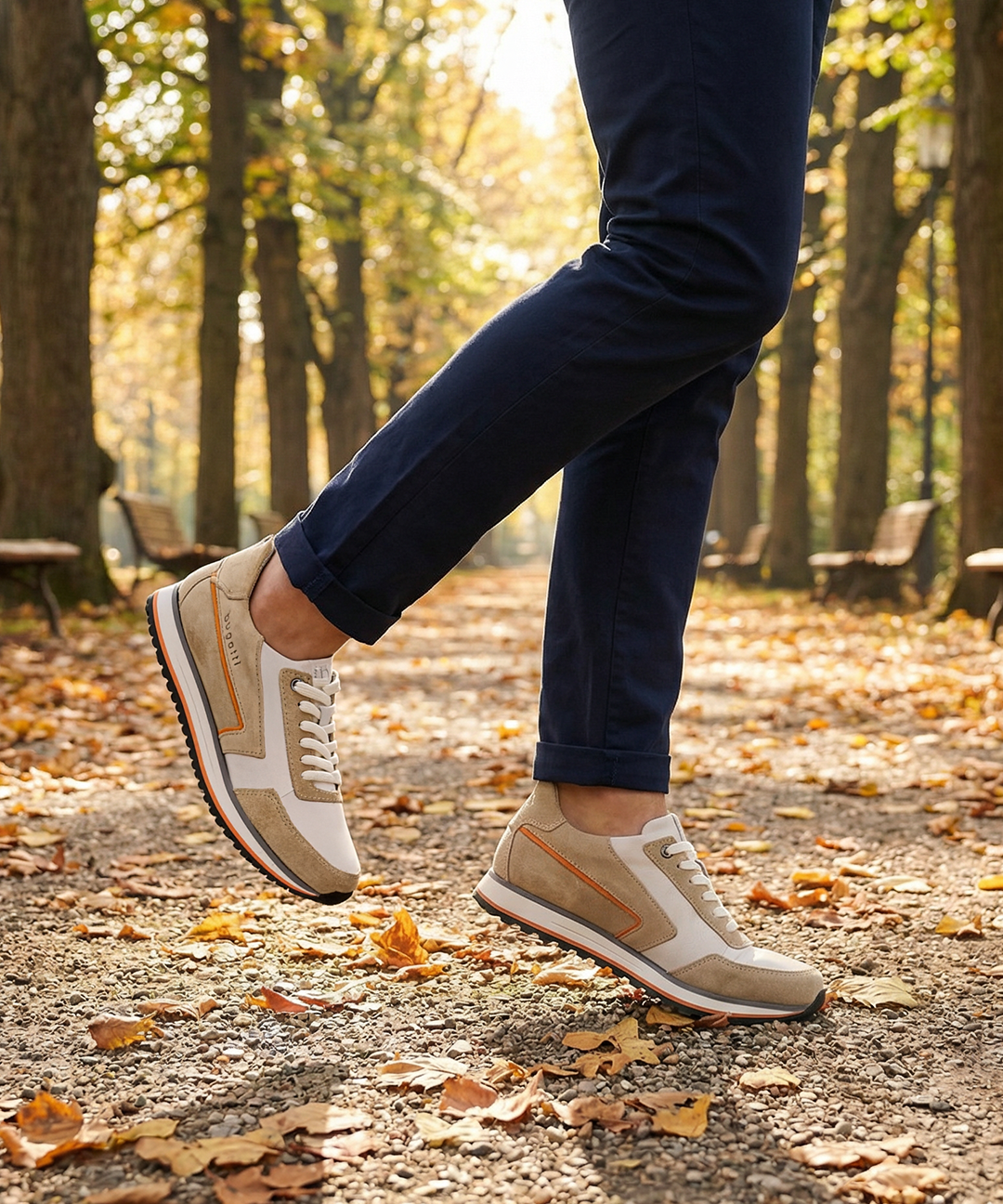 Lifestyle shot of bugatti Garnet Evo Sand sneakers in leather and suede, styled with navy trousers while walking on a path.