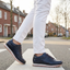 Lifestyle view of bugatti Garnet Evo dark blue leather sneakers with orange laces on a crosswalk.
