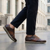 Lifestyle view of bugatti Garnet Evo dark brown premium leather sneakers with dark pants on a city street.