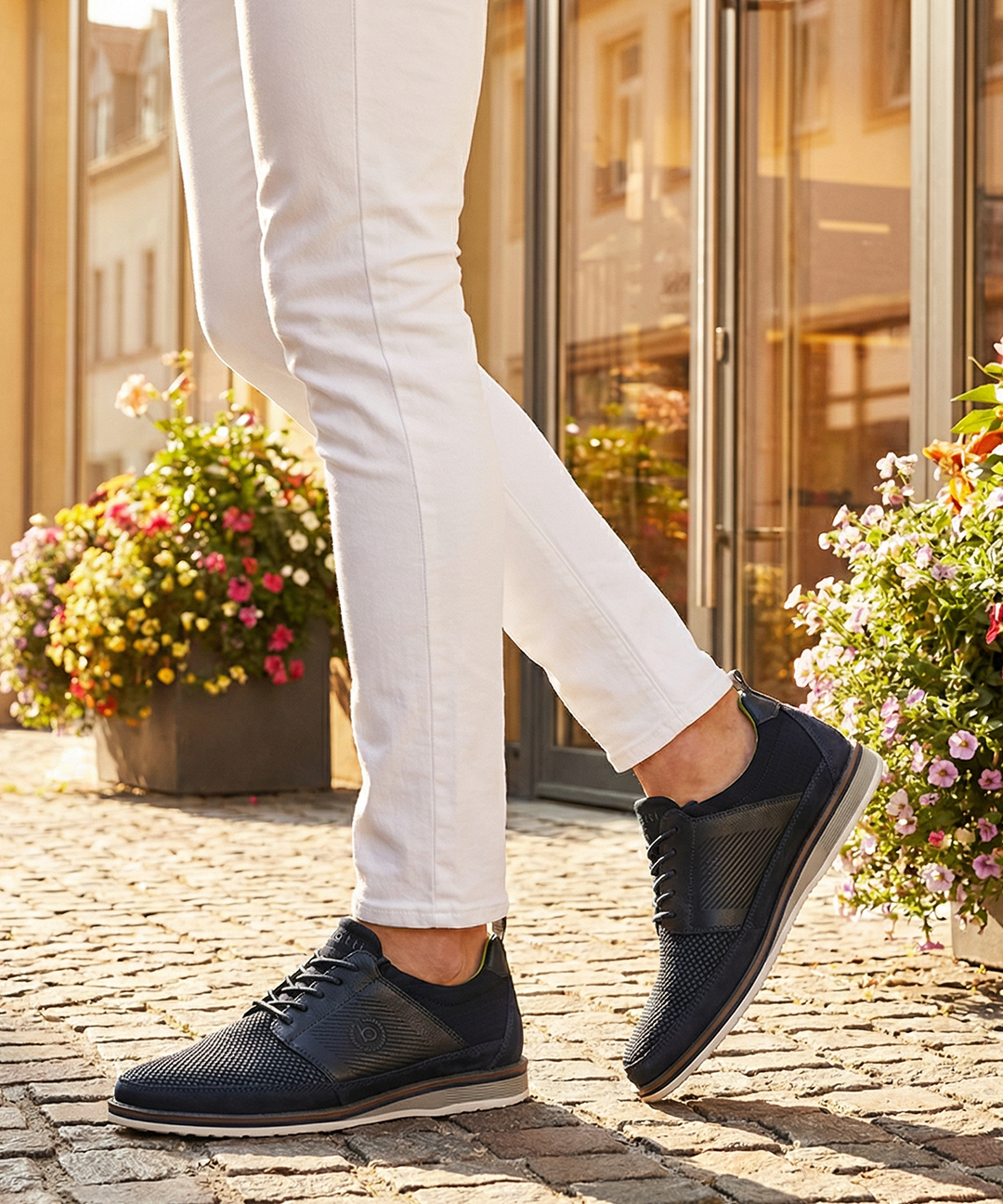 Lifestyle close-up of bugatti Sione Comfort dark blue casual shoes worn with white pants.
