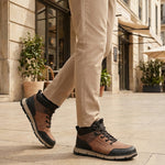Person wearing A cognac Men's bugatti Outdoor Sneakers featuring a round toe plain toe, zero heels heel. Made from synthetic with a durable eva outsole, this laces design offers both style and comfort. on a city street.