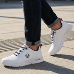 Lifestyle shot of the bugatti Nubola white sneakers, featuring black laces and logo detail, paired with dark denim jeans.

