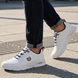 Lifestyle shot of the bugatti Nubola white sneakers, featuring black laces and logo detail, paired with dark denim jeans.
