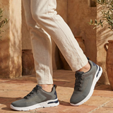 Lifestyle shot of bugatti Nubola dark gray sneakers with a white sole, paired with khaki-colored pants.
