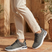 Lifestyle shot of bugatti Nubola dark gray sneakers with a white sole, paired with khaki-colored pants.
