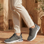 Lifestyle shot of bugatti Nubola dark gray sneakers with a white sole, paired with khaki-colored pants.
