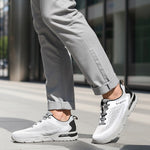 Cropped lifestyle shot of bugatti Nubola white sneakers with gray soles, black accents, and gray laces, worn with gray pants.