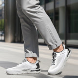 Cropped lifestyle shot of bugatti Nubola white sneakers with gray soles, black accents, and gray laces, worn with gray pants.