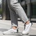 Cropped lifestyle shot of bugatti Nubola white sneakers with gray soles, black accents, and gray laces, worn with gray pants.