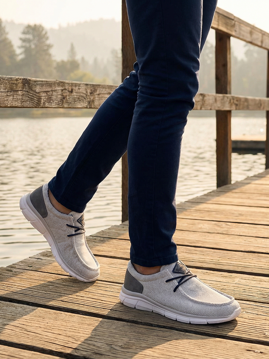 Lifestyle image of bugatti Soa light gray comfort mid-top sneakers with a gray heel patch, worn with navy pants.
