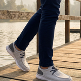 Lifestyle image of bugatti Soa light gray comfort mid-top sneakers with a gray heel patch, worn with navy pants.
