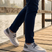 Lifestyle image of bugatti Soa light gray comfort mid-top sneakers with a gray heel patch, worn with navy pants.
